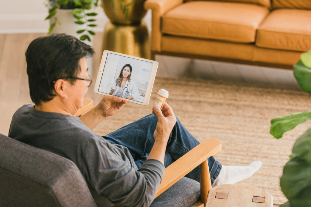 During a virtual appointment, a senior man discusses his current medications with a female doctor.