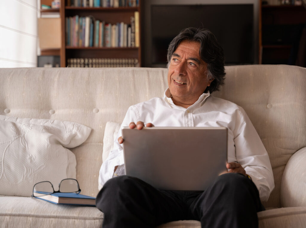 Portrait of a Latin American senior man on a laptop computer at home 
