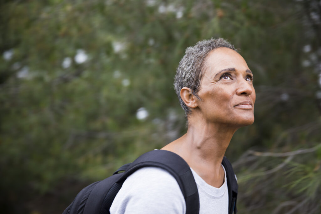A beautiful African American senior woman explores in nature while backpacking