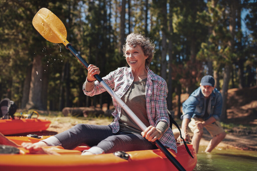 Portrait of happy senior paddling kayak in the lake.