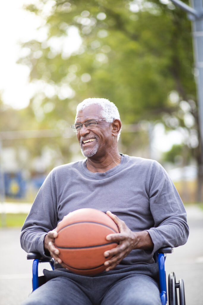 Portrait of a senior man in a wheelchair with a basketball.