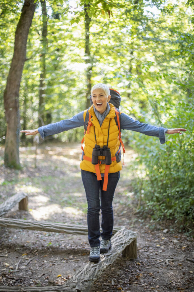 mature senior women in early 60 hiking in autumn forest,