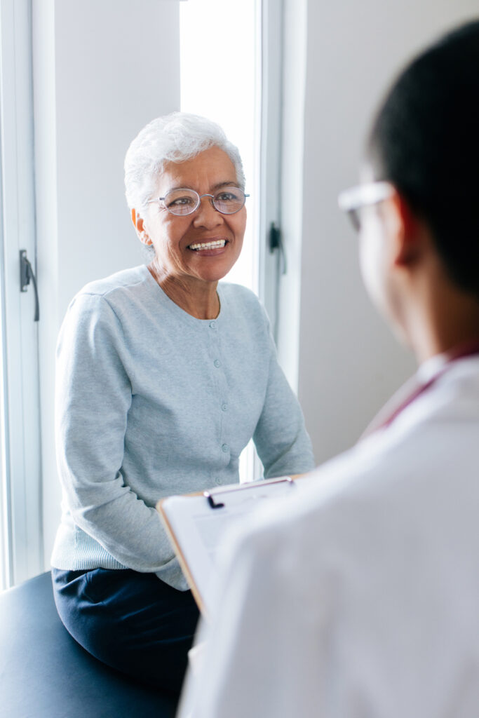 A senior female patient consulting at the doctor’s office and smiling.