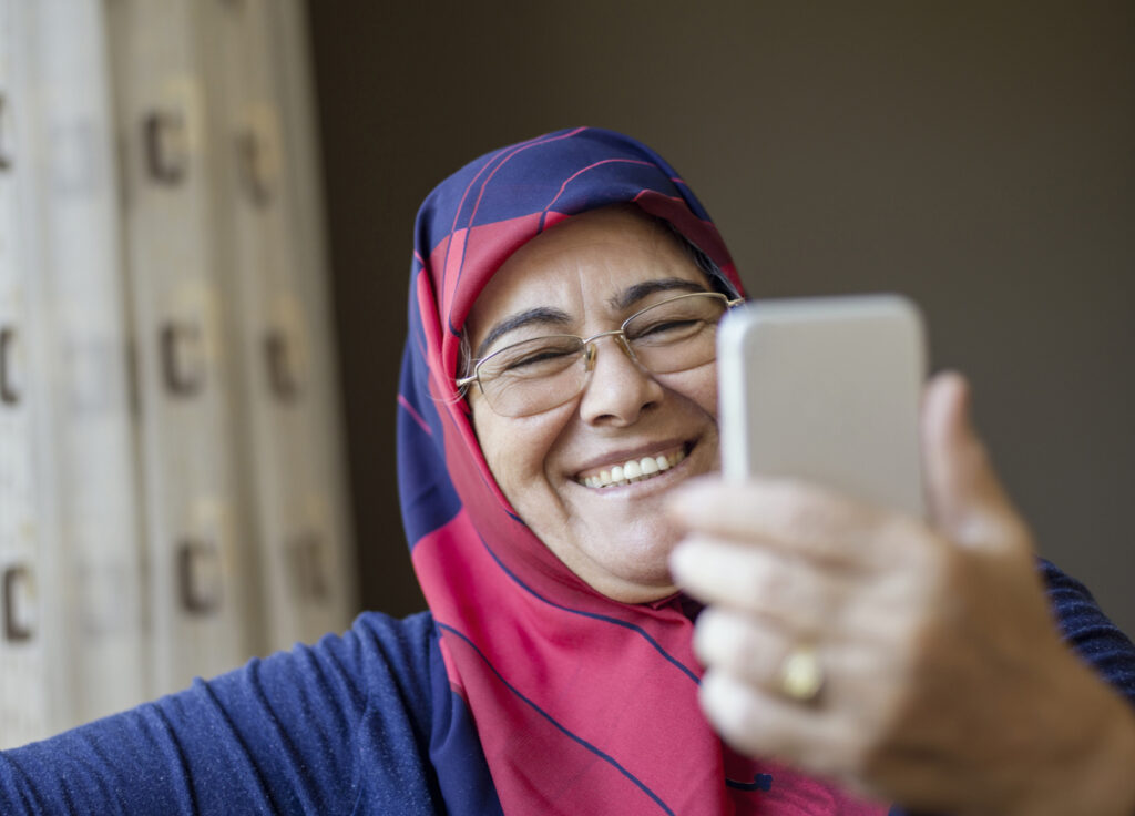 Senior woman wearing a headscarf taking a selfie, indoors