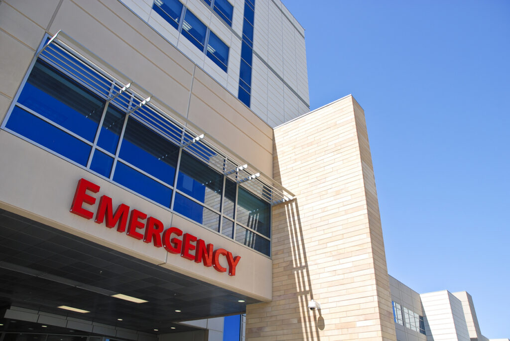 red emergency room sign outside modern hospital building