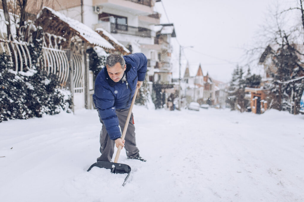 senior man with snow shovel, winter weather