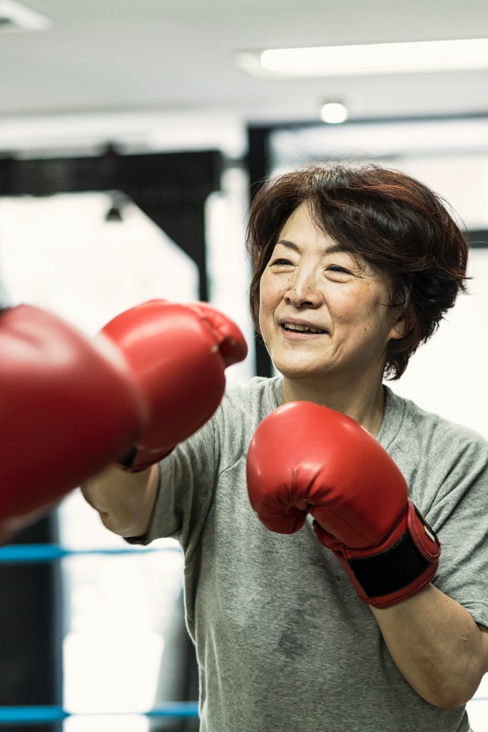 senior woman boxing with her trainer to stay fit