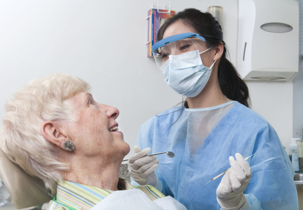 Female dental hygienist prepares to work on senior patient's teeth at a dental appointment
