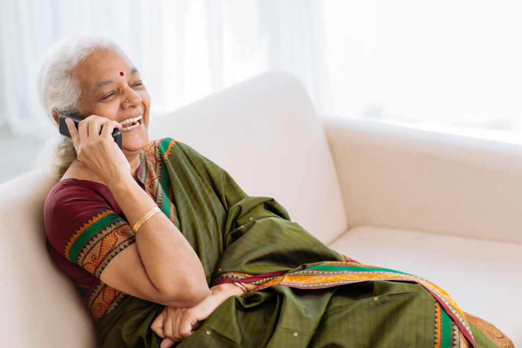senior woman wearing sari sitting on the couch and laughing on the phone