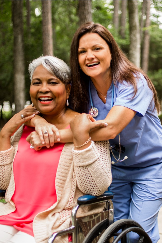 senior woman in wheelchair embracing nurse caretaker