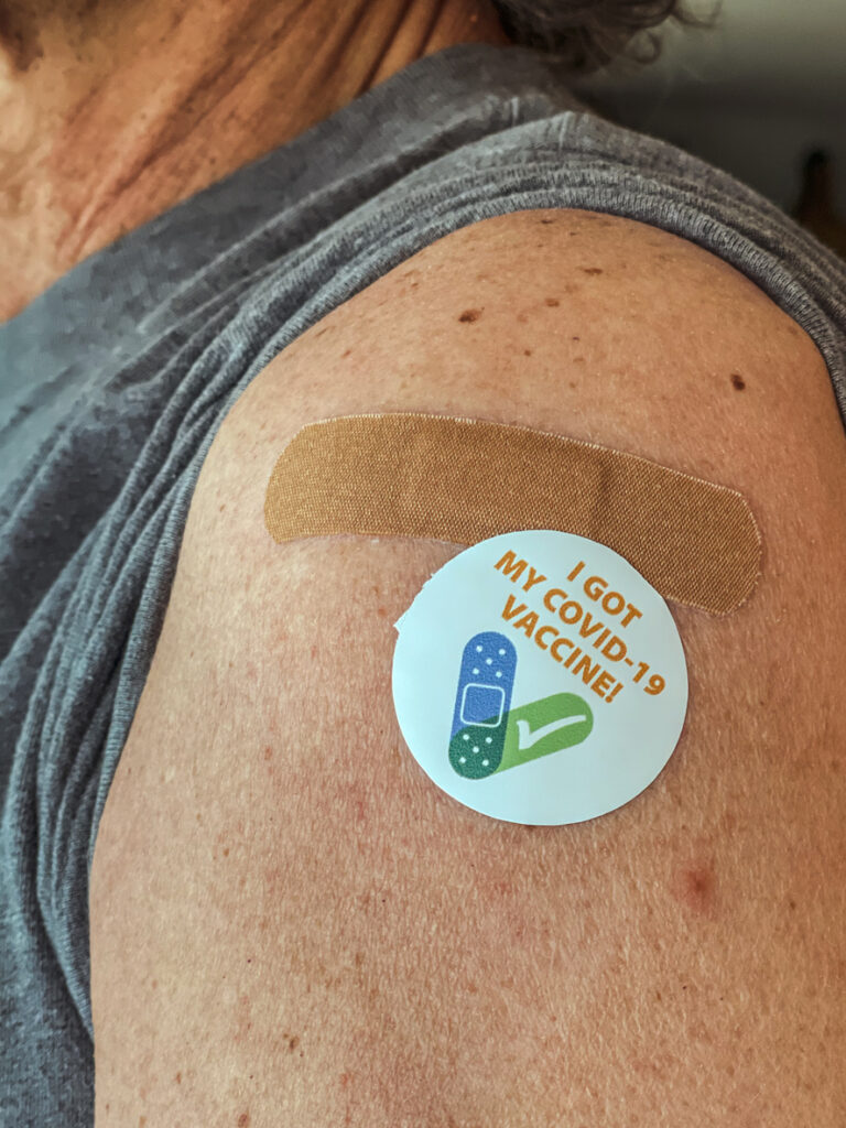 Senior adult man showing his adhesive his I got my covid-19 vaccination sticker and band aid.