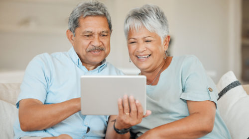 Mature couple both looking at a tablet computer.