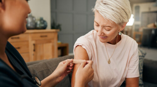 Covid vaccine, plaster and doctor with patient in a health consultation at a retirement house. Nurse, healthcare worker and elderly woman with a bandaid on her arm after a treatment in a nursing home.