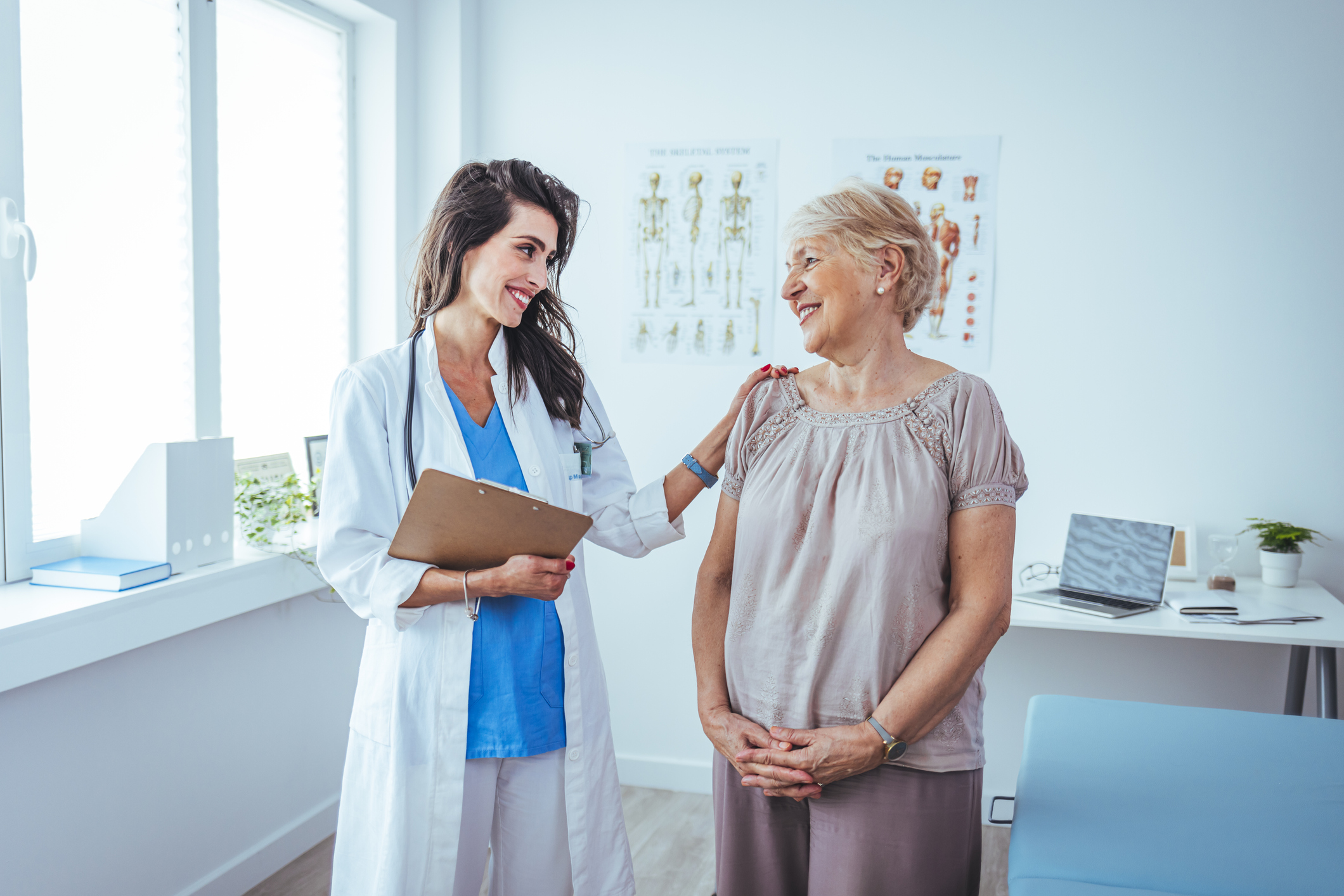 Female Senior Patient smiles while discussing medical history with her Female Doctor.