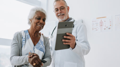 Doctor attending senior patient using digital tablet.