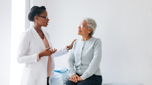 Female doctor standing next to senior patient and talking to her