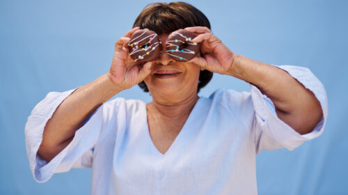 Donut, happy and portrait of woman on blue background with dessert, sweet treats and cake. Smile, food and face of mature person with snack for birthday, celebration and special event in studio